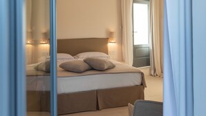 A hotel room with a bed, bedside lamps, a chair, and a view of the outside. - Dimora Biancarancio - Epoca Collection (Ostuni)