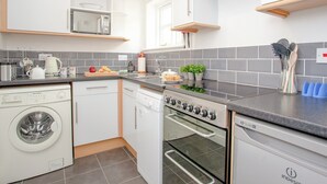A modern kitchen with white cabinets, a microwave, a stove, and a dishwasher. - Valley View - UK43268 (Upottery, near Honiton)