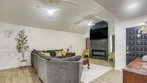 A living room with a grey sofa, a potted plant, a fireplace, and a dark door. - Centrally Located Eagle Pass Home w/ Pool! (Eagle Pass)