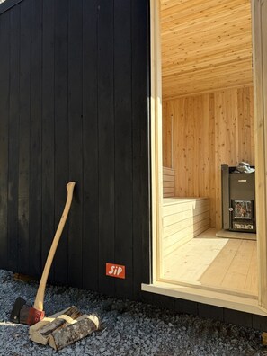 Ein Saunaraum mit Holzboden, einer Saunaanlage mit dem Aufdruck 'HARVIA' und einem Schild mit dem Schriftzug 'Sip'.