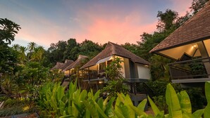A row of bungalow-style villas with thatched roofs, surrounded by lush tropical vegetation. - Loy Chalet (Krabi)