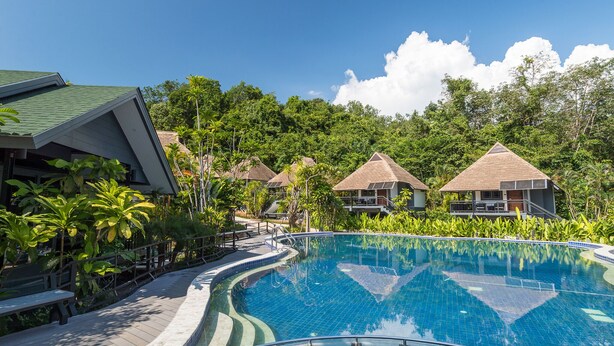 A resort with a swimming pool, palm trees, and thatched-roof structures. - Loy Chalet (Krabi)