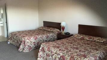A hotel room with two beds, a nightstand, and a lamp.