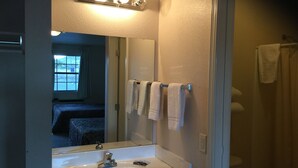 A bathroom with a white sink, a mirror, and a towel rack with towels. - Americana Inn (Sierra Blanca)
