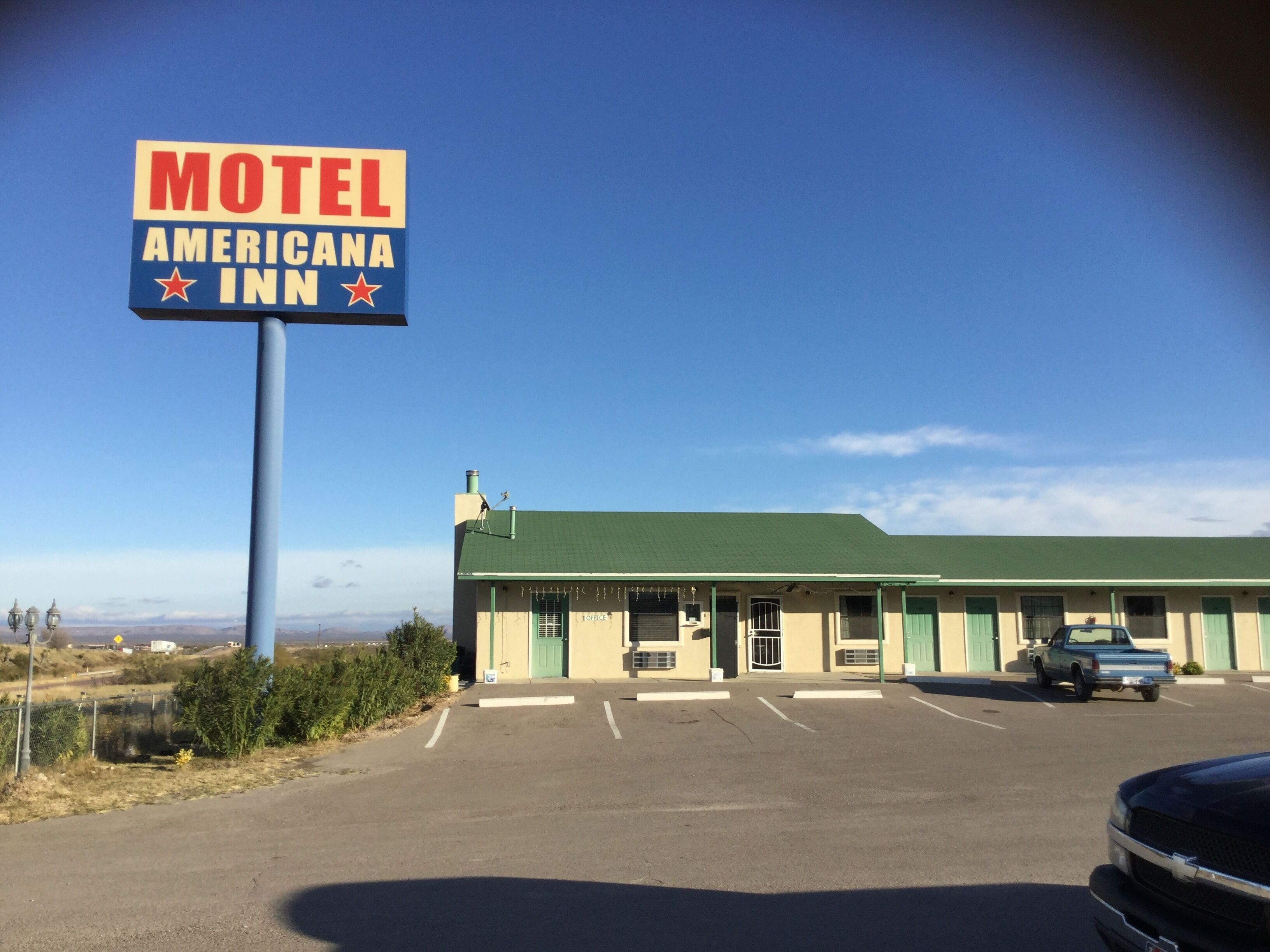A motel with a green roof and a sign that reads "Motel Americana Inn".