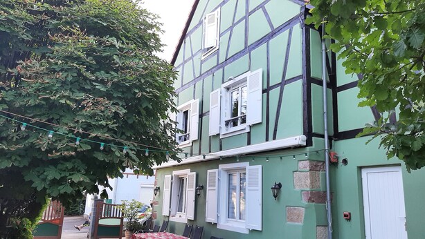 A traditional half-timbered house with multiple windows, a balcony, and a string of lights. - Le chat Vert, bright and modern 2-room apartment (Strasbourg)