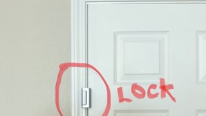 En vit dörr med ett lås och en röd etikett med texten ”LÅST”.