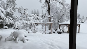 Ett snötäckt utomhusområde med en träpergola och en lusthus.