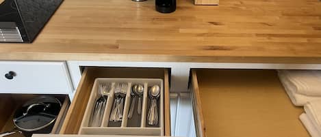 Cucina con piani di lavoro in legno, una macchina da caffè, un portacoltelli e un organizer da cassetti con utensili.