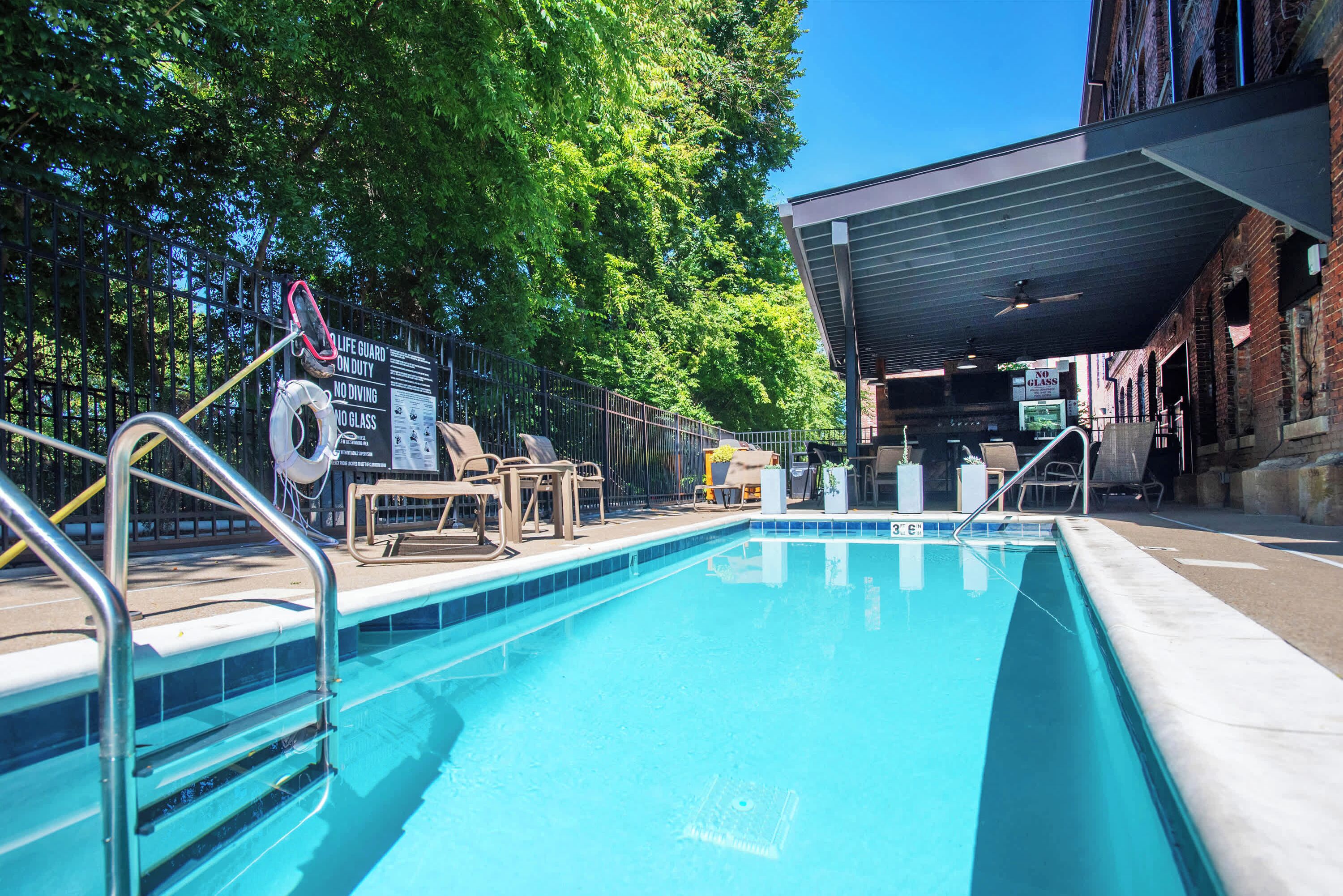 A swimming pool with lounge chairs and a covered area.