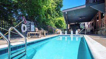 A swimming pool with lounge chairs and a covered area.
