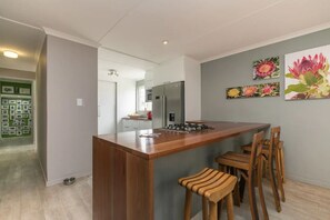 Une cuisine moderne dotée d’un îlot central, de tabourets de bar et d’un réfrigérateur.