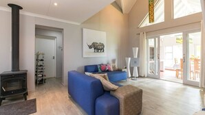 Un salon moderne avec un canapé bleu, une cheminée et une grande fenêtre.