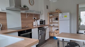 A modern kitchen with a microwave, oven, and dishwasher. There is a wooden countertop, a sink, and a window with a view. - Between Nausicaa and Wimereux, bright and spacious house, rated 3*. (Boulogne-sur-Mer)