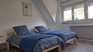 A bedroom with two wooden beds, a white wall with a framed picture, a window with blinds, and a radiator. - Between Nausicaa and Wimereux, bright and spacious house, rated 3*. (Boulogne-sur-Mer)