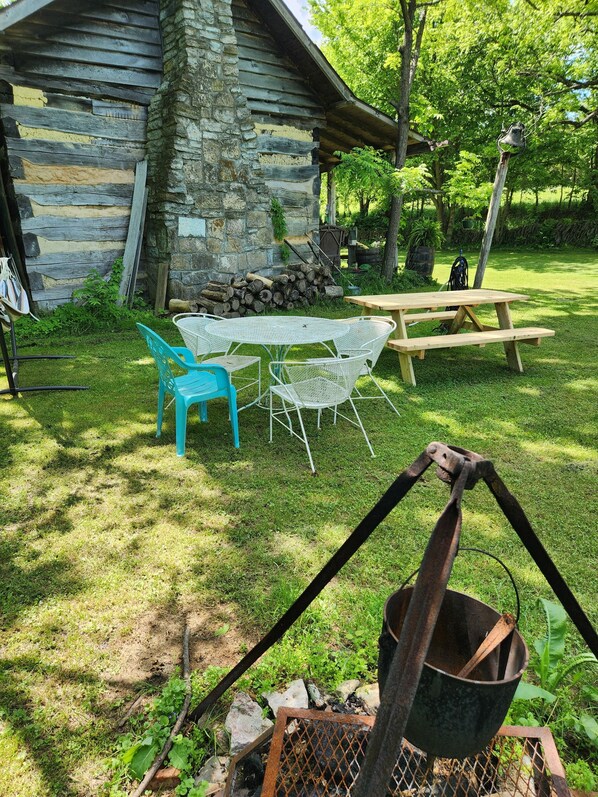 Una cabaña rústica con fachada de piedra, una terraza de madera y una mesa de picnic.
