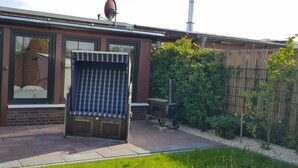 Um pátio com churrasqueira, porta de correr de vidro e parede de tijolos.