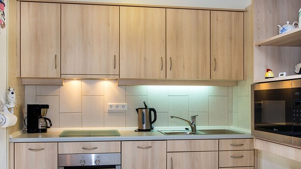 Eine moderne Küche mit Holzausstattung, Backofen, Kaffeemaschine und Mikrowelle.