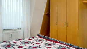 Ein Schlafzimmer mit einem Bett, einem Holzschrank und einem Fenster mit Vorhängen.