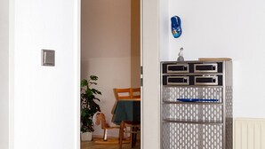 Ein Zimmer mit Holzboden, einem Metallschrank mit Schubladen, einem Holzstuhl, einem Tisch mit grüner Tischdecke und einem Topfpflanzen.