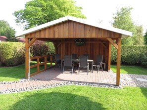 Une terrasse extérieure en bois, avec une table et des chaises, entourée d’une clôture en bois et d’une enseigne sur laquelle on peut lire « Beck’s ».