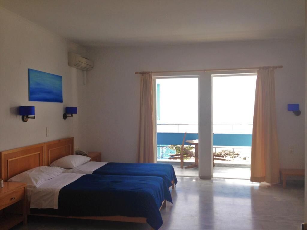 A hotel room with two beds, a balcony with a view, and a painting on the wall.