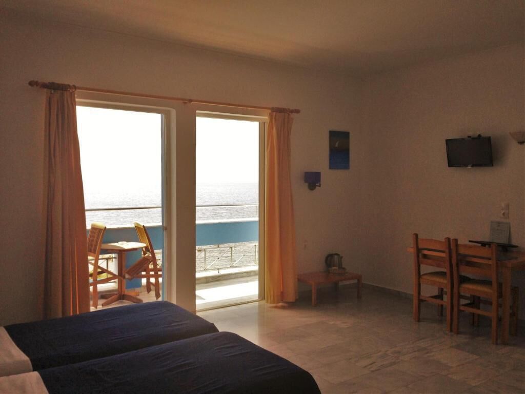Habitación de hotel con cama, escritorio y una silla. Cuenta con ventana con cortinas, una mesita y televisor en la pared.