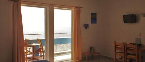 Habitación de hotel con cama, escritorio y una silla. Cuenta con ventana con cortinas, una mesita y televisor en la pared.