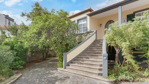 Ein Kopfsteinpflasterweg führt zu einem Haus mit einer Treppe.