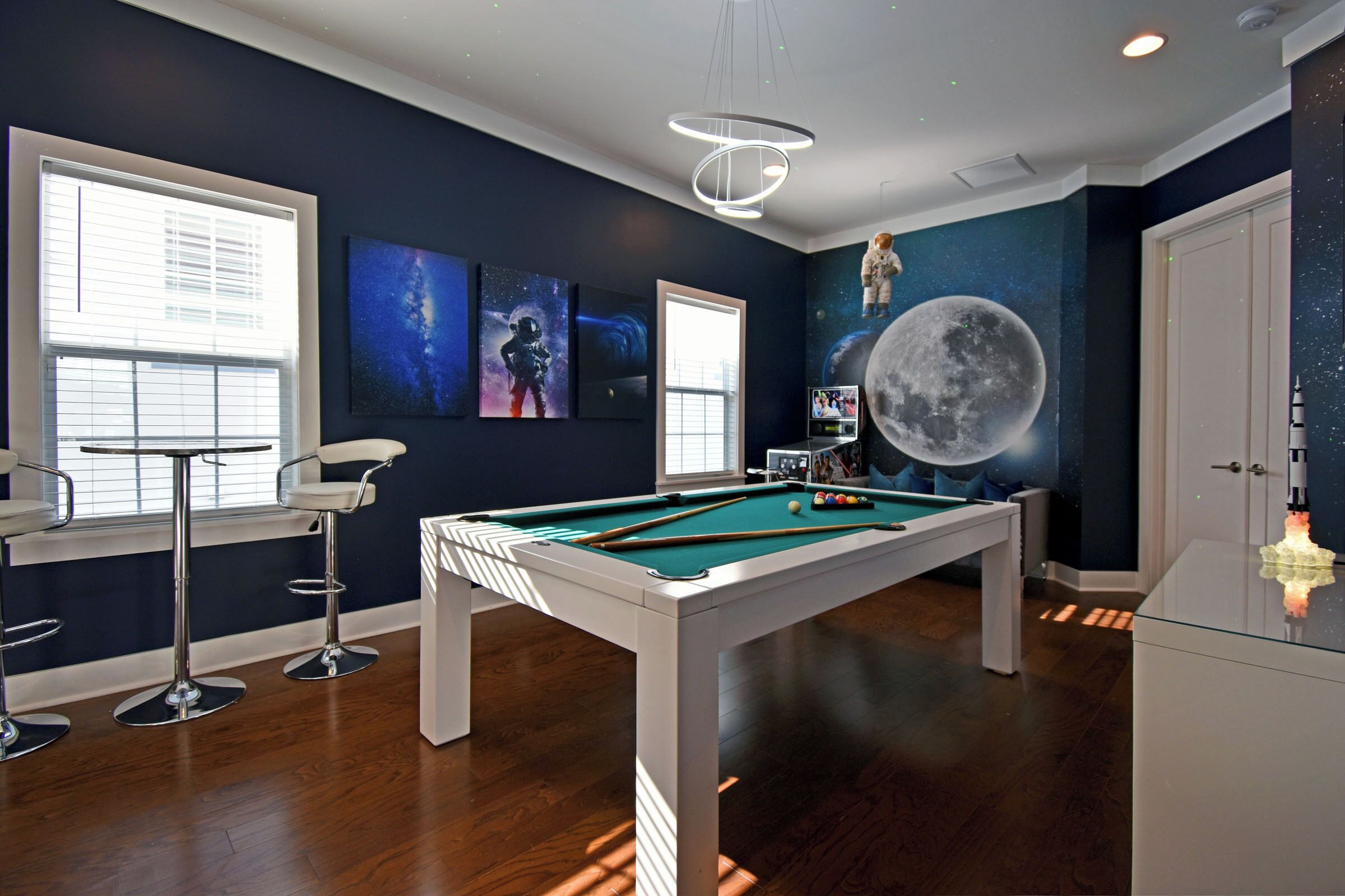 A pool table with a space-themed mural, a billiards cue rack, and a billiard ball rack.