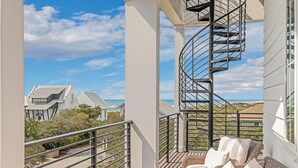 A balcony with a spiral staircase, wicker furniture, and a view of houses and the ocean. - Grayt Joy|Private Community Beach Access|Unobstructed Gulf Views (Santa Rosa Beach)