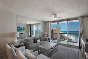 A spacious living room with a large window offering a view of the beach and ocean.