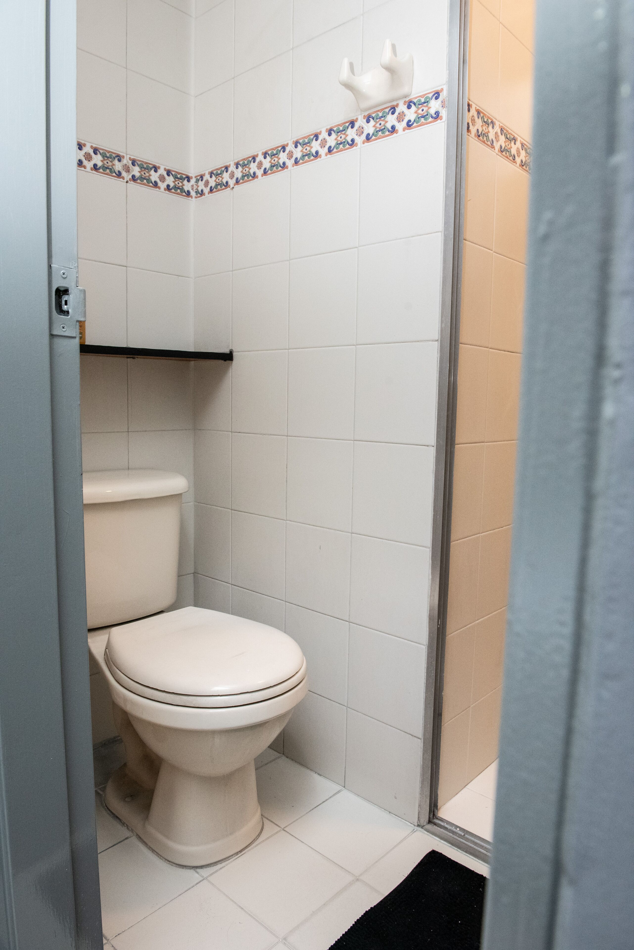 A bathroom with a white toilet, a shower area, and a tiled floor.