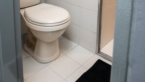 Une salle de bain avec des toilettes blanches, un espace douche et un sol carrelé.