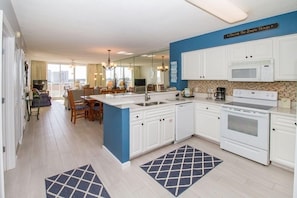 Una cocina moderna con armarios blancos, una isla central y un comedor con vistas.