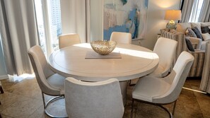 Una mesa de comedor redonda con un centro de mesa tejido, rodeada de seis sillas tapizadas.