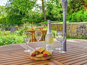 A round wooden table with a bottle of Freixenet Prosecco, three wine glasses, and a bowl of strawberries and biscuits. - 3 bedroom accommodation in Westbury-sub-Mendip (Westbury-sub-Mendip)