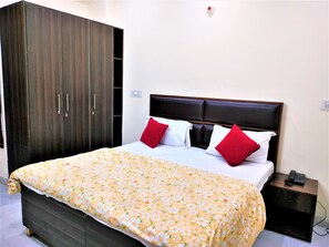 Una habitación de hotel con una cama, un armario y una mesita de noche con teléfono.