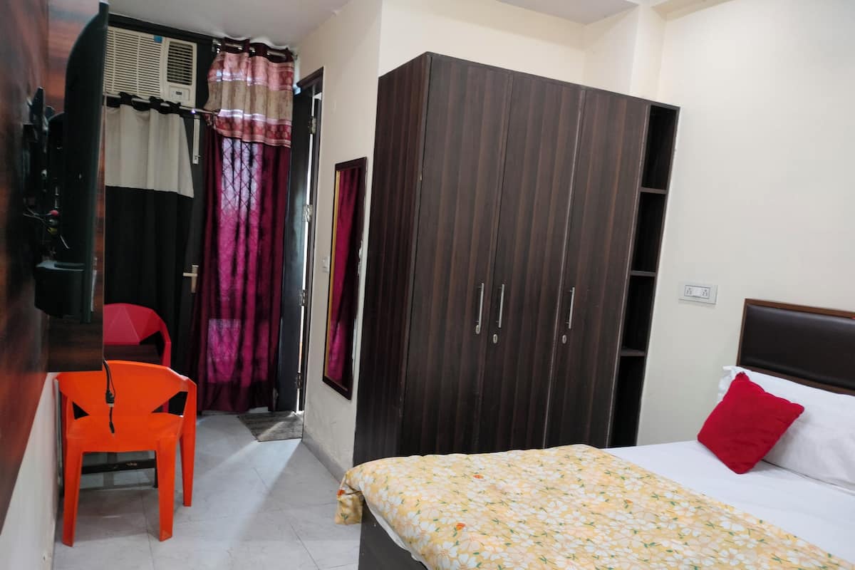 A bedroom with a bed, a wardrobe, a chair, and a window with curtains.