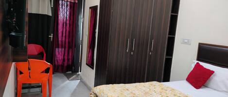 A bedroom with a bed, a wardrobe, a chair, and a window with curtains.