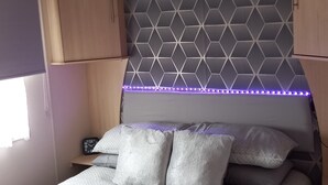 Ein Schlafzimmer mit einem Bett, einem Nachttisch, einer Uhr und einer Wand mit geometrischem Muster.