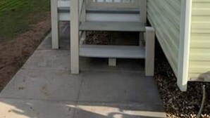 Ein Mobilheim mit Veranda und kleiner Terrasse.