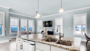A spacious kitchen with a large island, white cabinetry, and a view of the ocean.