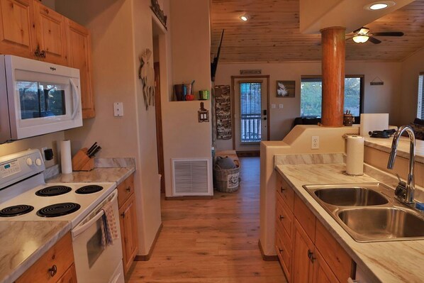 A kitchen with wooden cabinets, a white stove, and a stainless steel sink. - Entire Cozy Cabin @ Bison Ranch White Mountains (Overgaard)