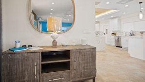 A modern kitchen with white cabinets, a wooden countertop, and a large mirror above a decorative cabinet. - Exquisite Courtyard Villa on St. Thomas East End / Ocean Views + Modern Comfort (St Thomas)