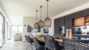 Een moderne keuken met een eethoek, met hanglampen, een houten tafel en zwarte stoelen.