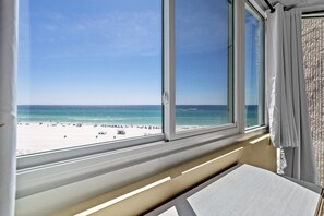 A room with a large window overlooking a beach.