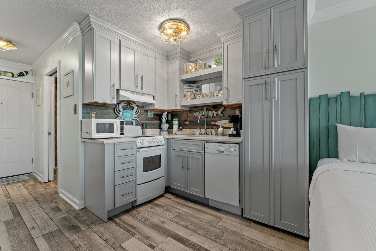 A compact kitchen with white cabinetry, a microwave, an oven, and a dishwasher.