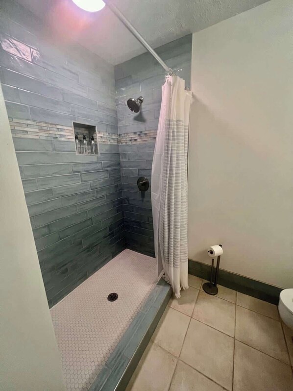 A small, enclosed shower area with a tiled floor and a showerhead.