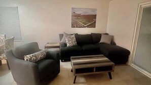 A living room with a black sofa, a black armchair, and a wooden coffee table.